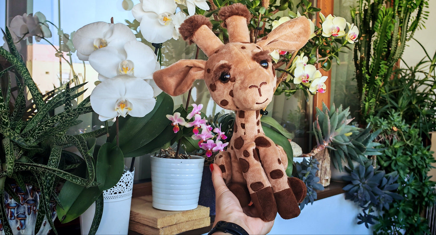 Plush giraffe toy held in front of a plant-filled background