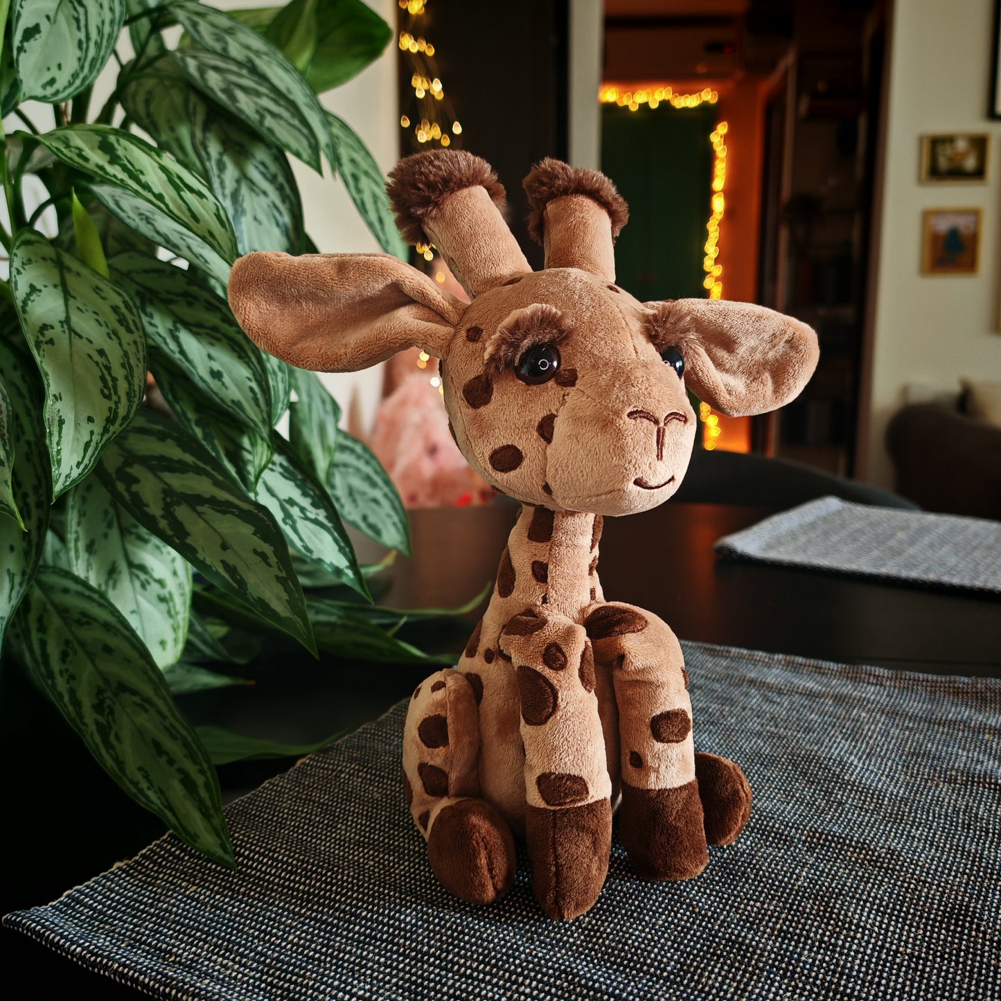 Plush giraffe toy on a table with a plant in the background
