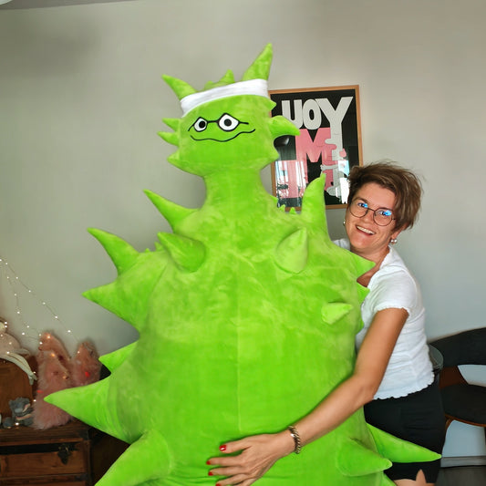 Person holding a Giant Emory Alien plush in a living room.